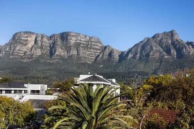 a mountain in the background of a resort with a palm tree at The Bergzicht Guest Suite in Cape Town