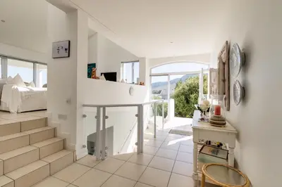 a white room with a bed and a staircase at 42 on 4th in Hermanus