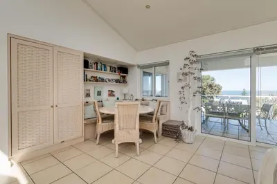 a dining room with a table and chairs and a balcony at 42 on 4th in Hermanus