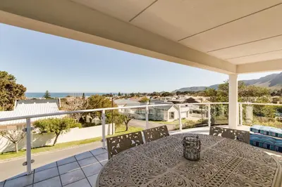 a table on a balcony with a view of the ocean at 42 on 4th in Hermanus