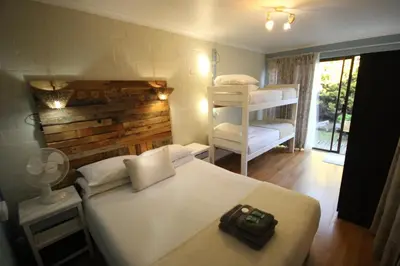 a bedroom with a bed and two bunk beds at Saltycrax Backpackers and Surf Hostel in Bloubergstrand