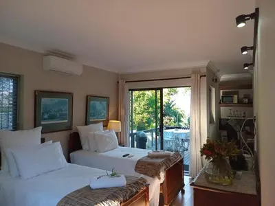 a bedroom with two beds and a balcony at The Greens Guesthouse in Bellville