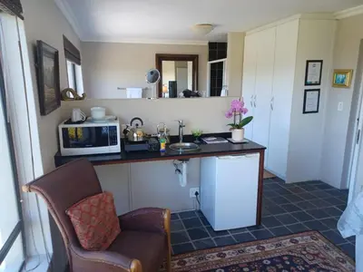 a kitchen with a counter with a microwave and a chair at The Greens Guesthouse in Bellville