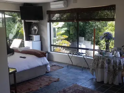 a bedroom with a bed and a large window at The Greens Guesthouse in Bellville