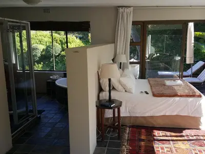 a bedroom with a bed with a lamp and a tub at The Greens Guesthouse in Bellville
