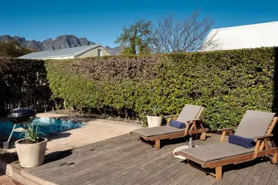two lounge chairs sitting on a deck next to a pool at Cook's Cottage in Franschhoek