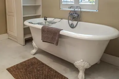 a white bath tub in a bathroom with a window at Cook's Cottage in Franschhoek