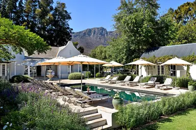 a swimming pool with lounge chairs and umbrellas at Lavender Farm Boutique Guest House in Franschhoek