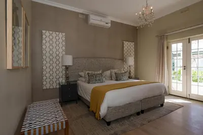 a bedroom with a large bed and a chandelier at Lavender Farm Boutique Guest House in Franschhoek