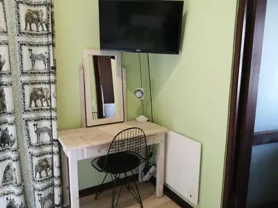 a desk with a chair and a television on a wall at a Vue Guesthouse in Somerset West
