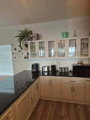 a kitchen with white cabinets and a black counter top at HERMANUS , SANDBAAI holiday house in Hermanus