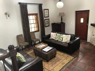 a living room with two leather couches and a table at Hemel en Aarde cottages in Hermanus