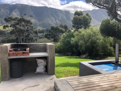 a concrete structure with a swimming pool next to a mountain at Hemel en Aarde cottages in Hermanus
