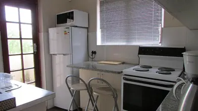 a kitchen with a stove and a white refrigerator at Pinewoods Rest in Somerset West