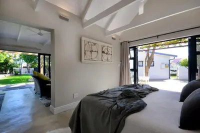 a bedroom with a bed and large sliding glass doors at SAFFRON COTTAGE in Hermanus