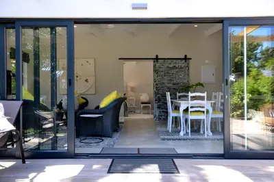 a living room with sliding glass doors and a table at SAFFRON COTTAGE in Hermanus