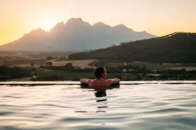 a man in a swimming pool with mountains in the background at 7 Koppies in Franschhoek