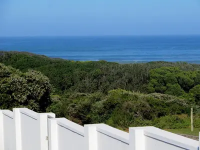 a white fence with the ocean in the background at Troon Beach Cottage Hermanus in Hermanus