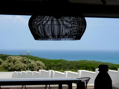 a table and chairs with a view of the ocean at Troon Beach Cottage Hermanus in Hermanus