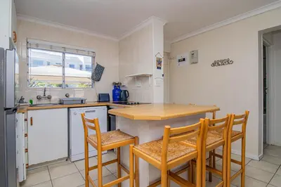 a kitchen with a table and chairs and a sink at 176 hbc in Hermanus