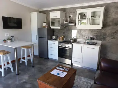 a kitchen with white cabinets and a table and a counter at Treyntjes Rivier Cottages in Caledon