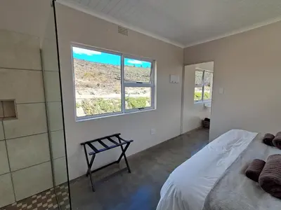a bedroom with a bed and a glass shower at Treyntjes Rivier Cottages in Caledon