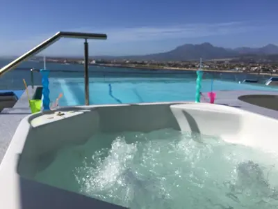 a bath tub sitting next to a swimming pool at GORDON's SHORE LUXURY APARTMENTS - Solar Powered in Gordonʼs Bay