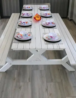 a wooden picnic table with plates of food on it at GORDON's SHORE LUXURY APARTMENTS - Solar Powered in Gordonʼs Bay