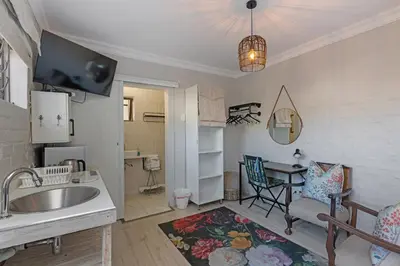 a kitchen and living room with a sink and a table at Petite Apartment in Bellville