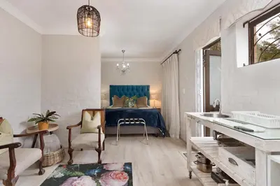 a bedroom with a bed with a blue headboard at Petite Apartment in Bellville