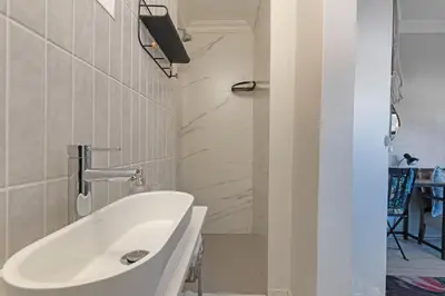 a bathroom with a white sink and a tub at Petite Apartment in Bellville