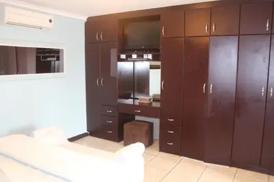 a living room with brown cabinets and a tv at Alyssa's Inn Boutique Guesthouse in Cape Town