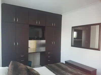 a bedroom with dark brown cabinets and a mirror at Alyssa's Inn Boutique Guesthouse in Cape Town