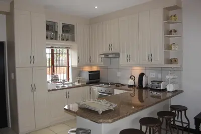 a kitchen with white cabinets and a counter with bar stools at Alyssa's Inn Boutique Guesthouse in Cape Town