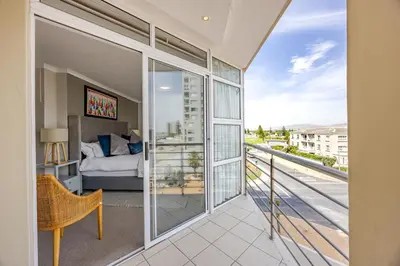 a bedroom with a view of a bed and a balcony at Luxury Ocean View Beachfront 2 bed apartment -206 The Waves, Blouberg, Cape Town in Bloubergstrand