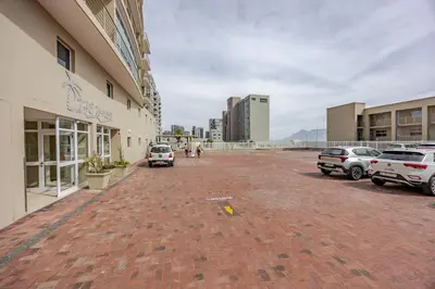 a brick parking lot with cars parked in front of a building at Luxury Ocean View Beachfront 2 bed apartment -206 The Waves, Blouberg, Cape Town in Bloubergstrand