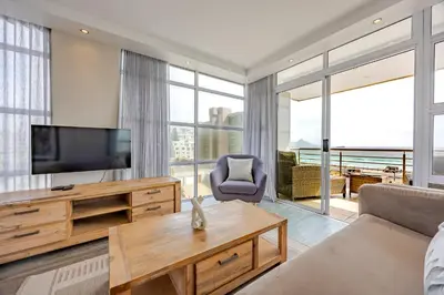 a living room with a television and a couch at Luxury Ocean View Beachfront 2 bed apartment -206 The Waves, Blouberg, Cape Town in Bloubergstrand