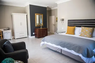 a bedroom with a large bed and a chair at The Whale on Main B&B in Hermanus
