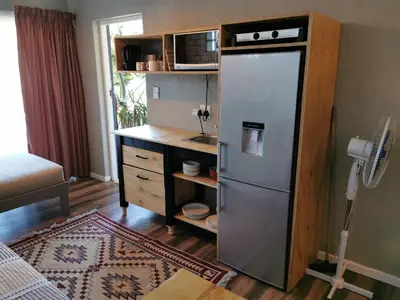 a kitchen with a refrigerator and a desk with a microwave at Tranquility in Parow