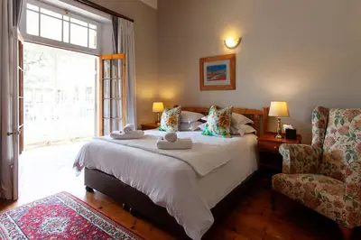 a bedroom with a large bed and a chair at The Habit Guesthouse in Worcester