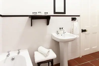 a white bathroom with a sink and a mirror at The Habit Guesthouse in Worcester