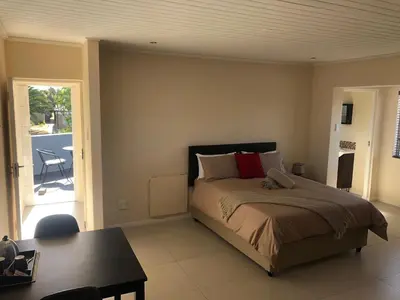 a bedroom with a bed and a table and a patio at Flamingo Palms in Table View
