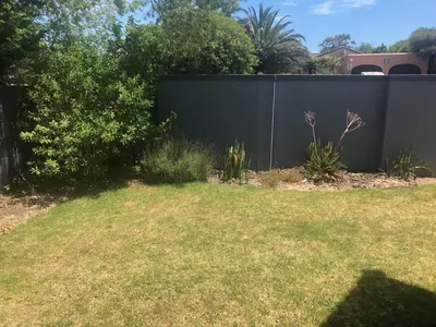 a black fence in a yard with grass at Flamingo Palms in Table View