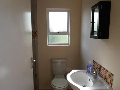 a bathroom with a toilet and a sink and a window at Flamingo Palms in Table View