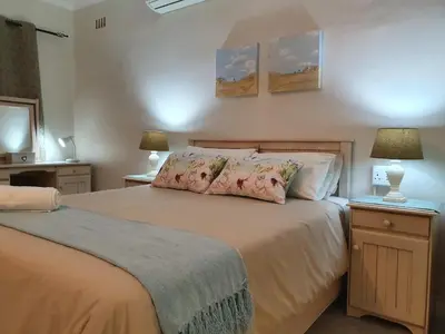 a bedroom with a large bed with two lamps at Tyger Hills Guest House in Bellville