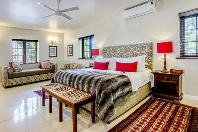 a bedroom with a large bed with red pillows at Vredenburg Manor House in Somerset West