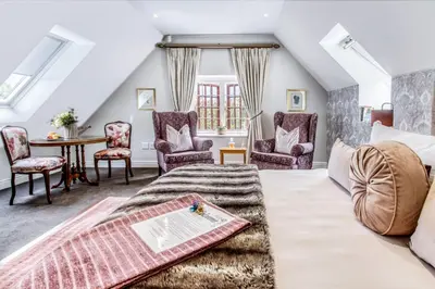 a living room with a bed and chairs and a table at Vredenburg Manor House in Somerset West