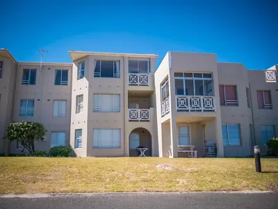 a large apartment building with a lawn in front of it at 123 hbc in Hermanus