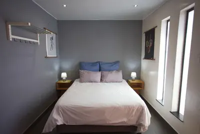 a bedroom with a bed with blue pillows and two lamps at Panorama Indlu in Cape Town
