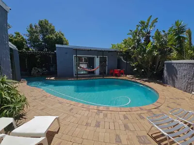 a small swimming pool with chairs and a playground at Panorama Indlu in Cape Town